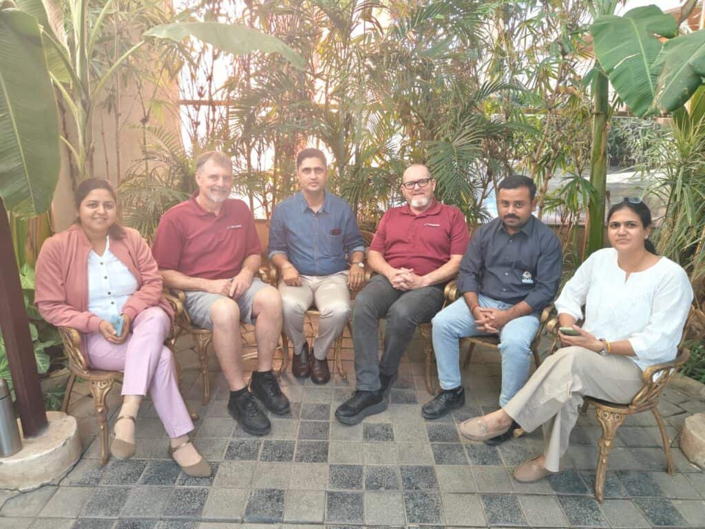 Group photo of the UUNIQE Ventures team with international business visitors, seated together in a garden setting after a successful factory visit and business meeting, celebrating collaboration and global partnerships.