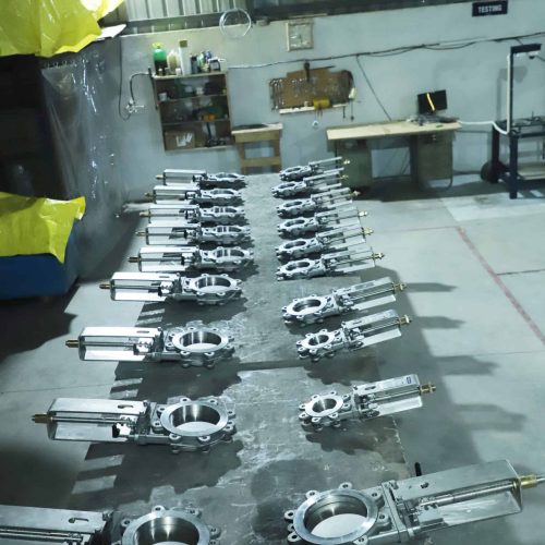 Industrial Knife Gate Valves arranged on a quality inspection table inside a valve manufacturing facility. Precision-engineered stainless steel valves undergo final testing and inspection to ensure leak-tight sealing, dimensional accuracy, and reliable industrial performance.
